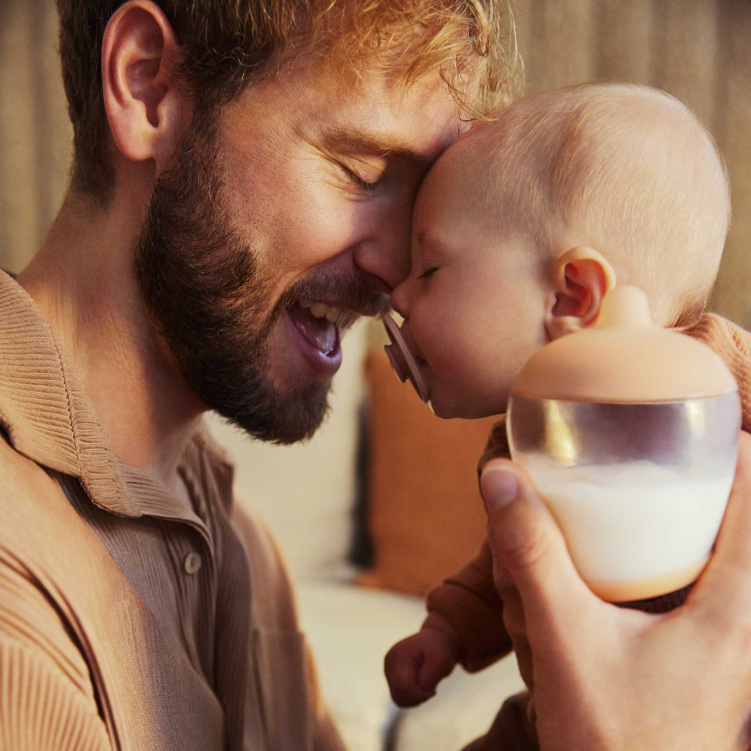 Father holding baby with Emulait Classic Bottle and Rose Pacifier